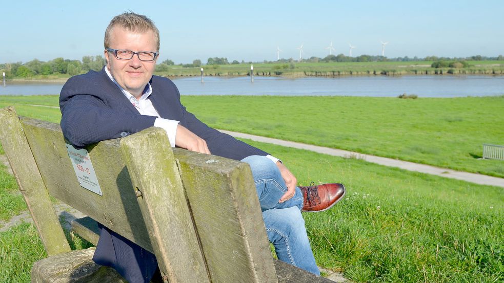 Westoverledingens Bürgermeister Theo Douwes sitzt auf dem Deich beim Schöpfwerk des Muhder Sieltiefs im Ortsteil Esklum, um von dort auf den Zusammenfluss von Leda und Ems zu blicken. Es ist ein strategisch wichtiger und geschichtsträchtiger Ort im Gemeindegebiet, den Douwes gern als Rastplatz für seine Radtouren nutzt. Foto: Fertig