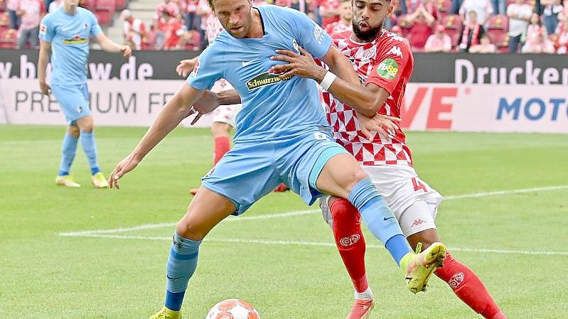 Freiburgs Lucas Höler versucht den Ball vor dem attackierenden Mainzer Jeremiah St. Juste abzuschirmen. Foto: Torsten Silz/dpa