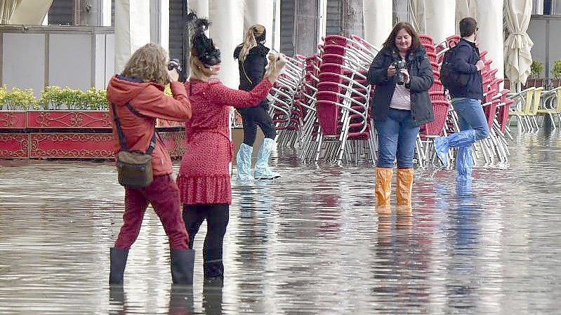 Menschen auf dem überfluteten Markusplatz in Venedig. Foto: Matteo Tagliapietra/LaPresse/dpa