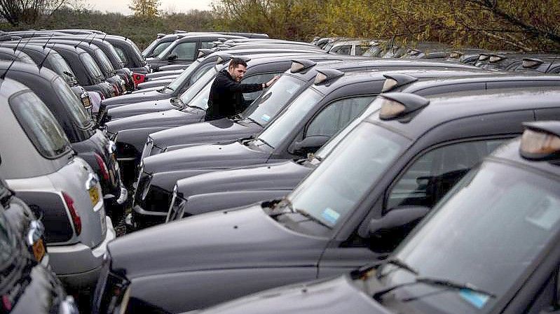 Dutzende während der Corona-Pandemie stillgelegte Taxis, die für London typischen „Black Cabs“, parken auf einer Freifläche. Foto: Victoria Jones/PA Wire/dpa