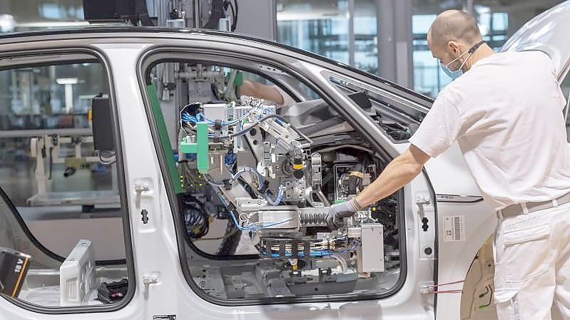 Ein Arbeiter arbeitet mit Mund-Nasen-Schutz an einem Auto. Foto: Matthias Rietschel/dpa-Zentralbild/dpa