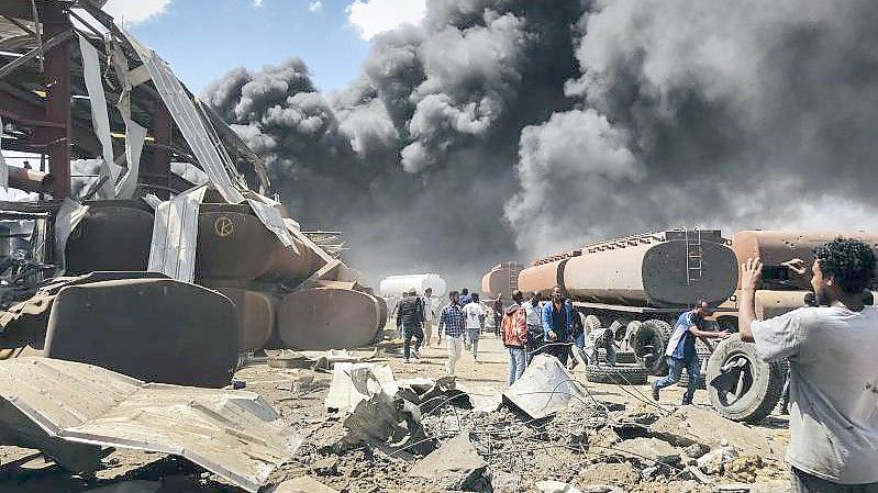 Menschen stehen nach einem Luftangriff auf die Hauptstadt der Region Tigray im Norden Äthiopiens vor schwarzen Rauchschwaden. Foto: UGC/AP/dpa/Archiv