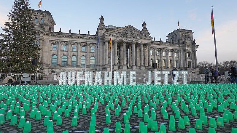 Ein Meer aus grünen Lichtern und der Schriftzug „Aufnahme Jetzt“ vor dem Reichstag in Berlin. Foto: Jörg Carstensen/dpa