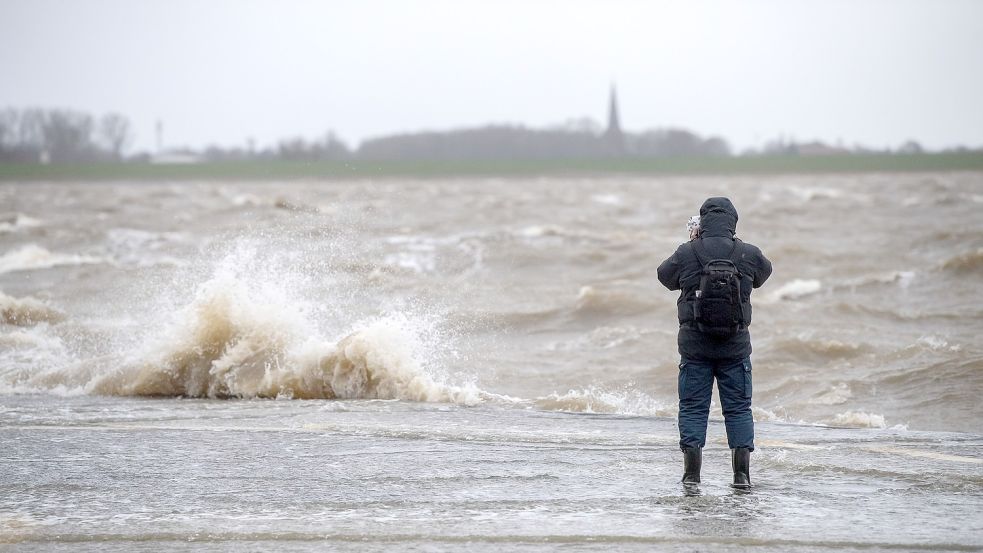 Ein Mann steht an der Kaimauer während einer Sturmflut, das Bild entstand in Bremerhaven. Foto: Schuldt/dpa