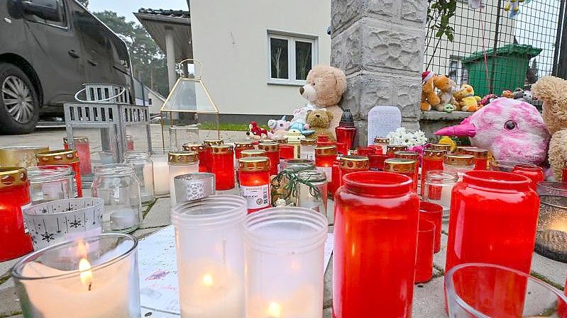 Kerzen und Plüschtiere für die Opfer vor dem Einfamilienhaus in Königs Wusterhausen im Landkreis Dahme-Spreewald. Foto: Patrick Pleul/dpa-Zentralbild/dpa