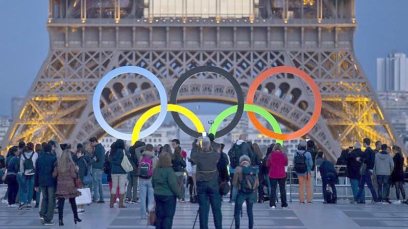 Die Olympischen Ringe leuchten am Fuße des Eiffelturms in Paris. Foto: Michel Euler/AP/dpa