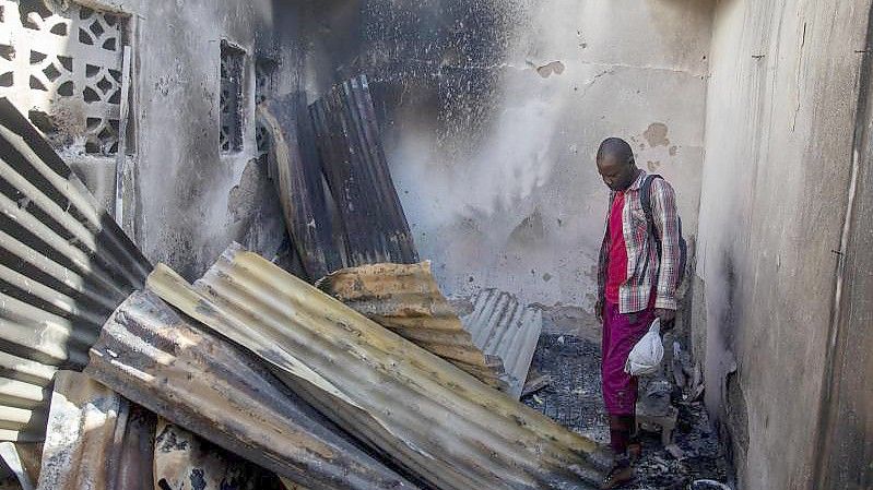 Ein Anwohner betrachtet das eingestürzte Blechdach eines bei der Explosion zerstörten Hauses. Foto: Odelyn Joseph/AP/dpa