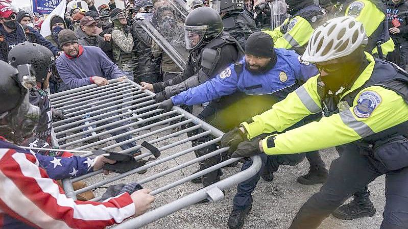 Trump-Anhänger versuchen am 6. Januar 2021, durch eine Polizeiabsperrung am US-Kapitol zu brechen. Foto: John Minchillo/AP/dpa