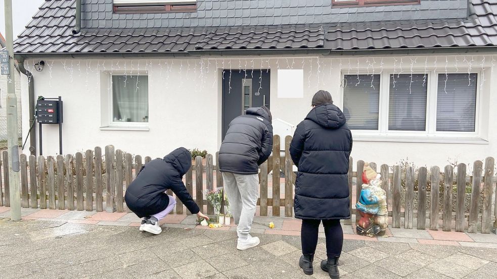 Hinter der weißen Fassade passierte das entsetzliche Verbrechen: Anwohner legen vor dem Haus in Glinde Blumen nieder. Foto: Peter Wüst/rtn