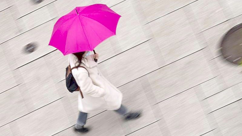 Regenwetter: Nur der Schirm bringt etwas Farbe ins Spiel. Foto: Frank Rumpenhorst/dpa