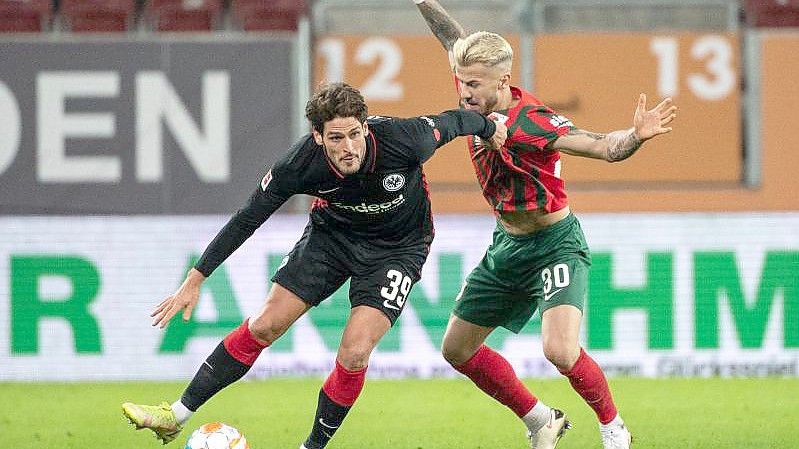 Goncalo Paciencia von Eintracht Frankfurt (l) schirmt den Ball gegen Augsburgs Niklas Dorsch ab. Foto: Matthias Balk/dpa