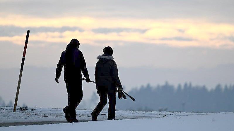 Morgendlicher Spaziergang kurz nach Sonnenaufgang auf einer schneebedeckten Anhöhe in Baden-Württemberg. Foto: Felix Kästle/dpa