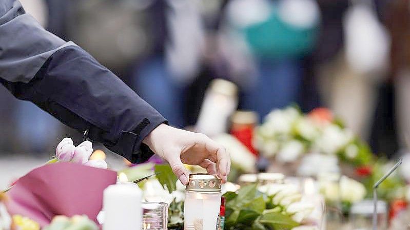 Menschen haben vor einem Gebäude der Heidelberger Universität Blumen und Kerzen niederlegt. Foto: Uwe Anspach/dpa