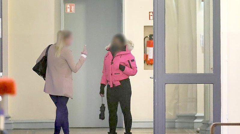 Zwei angeklagte Frauen warten vor einem Gerichtssaal im Strafjustitzgebäude in Hamburg auf den Beginn der Verhandlung. Foto: Ulrich Perrey/dpa