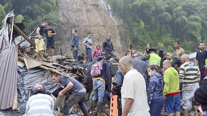 Rettungskräfte und Einwohner suchen zwischen den Trümmern der weggerissenen Häuser nach Überlebenden. Foto: Andres Otalvaro/AP/dpa