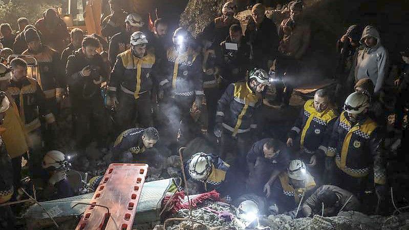 Mitglieder der syrischen Zivilverteidigung White Helmets versuchen, eine Familie aus den Trümmern eines zweistöckigen Hauses zu retten. Foto: Anas Alkharboutli/dpa