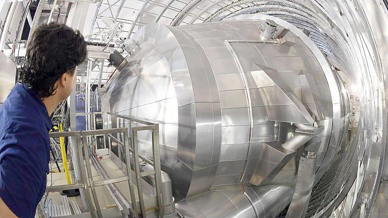 Ein Mitarbeiter des Karlsruher Tritium Neutrino Experiments (Katrin) am Karlsruher Institut für Technologie (KIT) blickt auf das Hauptspektrometer der Anlage. Mit dem Experiment soll die Masse von Neutrinos mit bis dato nicht möglicher Genauigkeit gemessen werden. Foto: Uli Deck/dpa