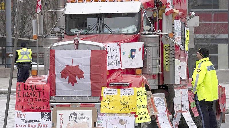 Ein Polizist in Ottawa im Gespräch mit einem Lastwagenfahrer, der sein Gefährt mit Schildern und Flaggen bedeckt hat. Foto: Adrian Wyld/The Canadian Press/AP/dpa