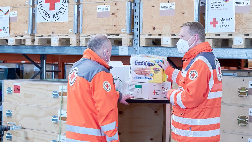 Mitarbeiter des Deutschen Roten Kreuzes (DRK) betrachten Hilfsgüter, die für einen Transport verladen werden sollen. Die Hilfsgüter werden per LKW nach Polen gebracht. Foto: Riedl/dpa