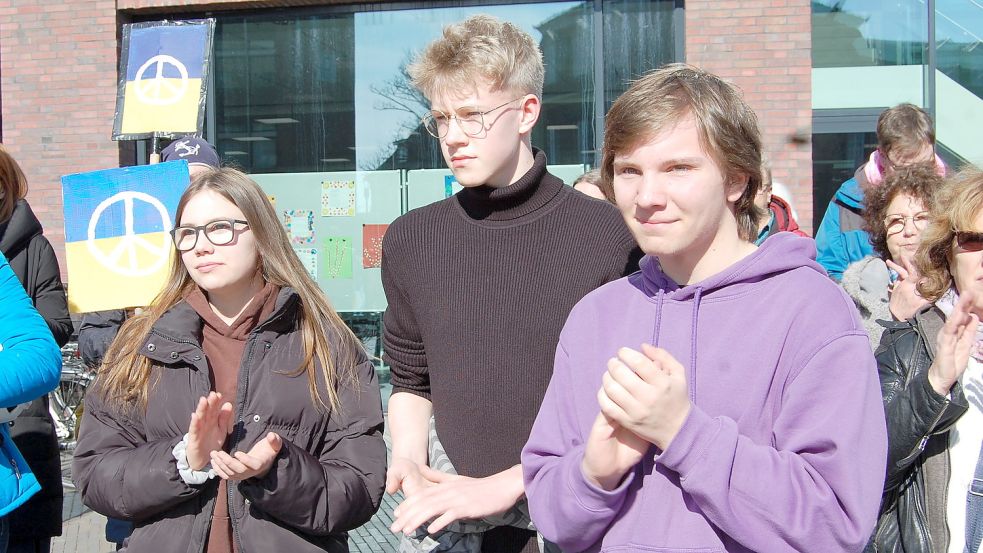 Leonie Kramer (von links), Mika Vogel und Damian Weerts aus Leer klatschen in die Hände, während die Gruppe Euroklang zum Abschluss der Kundgebung das Lied „We Shall Overcome" (Wir werden ,es′ überwinden)" anstimmt. Das Protestlied spielte in der US-Bürgerrechtsbewegung der 1960er Jahre eine wichtige Rolle. Foto: Schneider-Berents