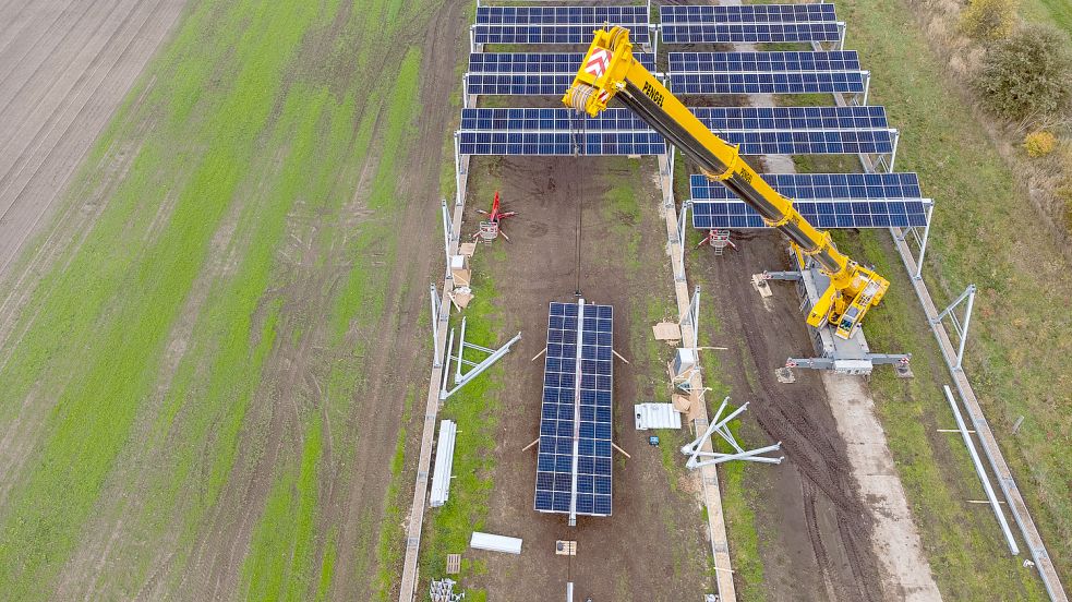 So könnte es auch in Emden aussehen: Mit einem Kran wird eine Agrar-Photovoltaik-Anlage aufgestellt (Aufnahme mit einer Drohne). Im Wendland ist die größte deutsche Agrar-Photovoltaik-Anlage entstanden. Das Pilotprojekt kombiniert Energie- und Landwirtschaft. Foto: P. Schulze/dpa