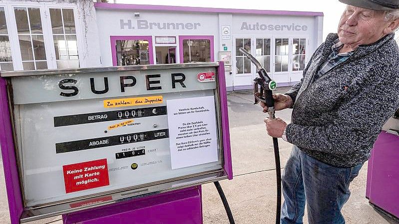 Hans Brunner steht an einer Zapfsäule seiner Tankstelle. Die Tankstelle zeigt Benzin- und Dieselpreise halbliterweise an. Foto: Armin Weigel/dpa