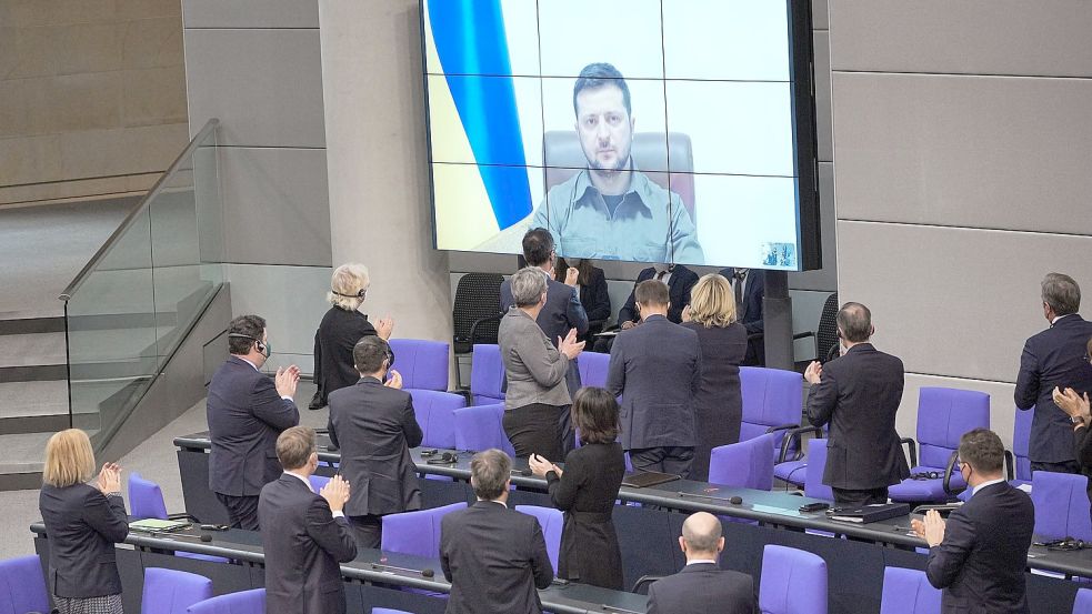 Der ukrainische Präsident Wolodymyr Selenskyj spricht auf einer Videoleinwand im Bundestag und bekommt Applaus von der Bundesregierung. Foto: Michael Kappeler/dpa