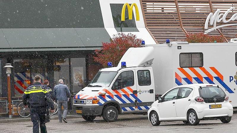 Polizisten ermittelt am Tatort, wo zwei Männer nach Schüssen in einem Schnellrestaurant ums Leben gekommen sind. Foto: Vincent Jannink/ANP/dpa