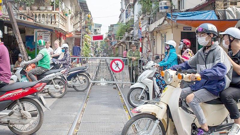 Motorradfahrer überqueren die Train Street in Hanoi, die für Fußgänger gesperrt ist. Foto: Chris Humphrey/dpa