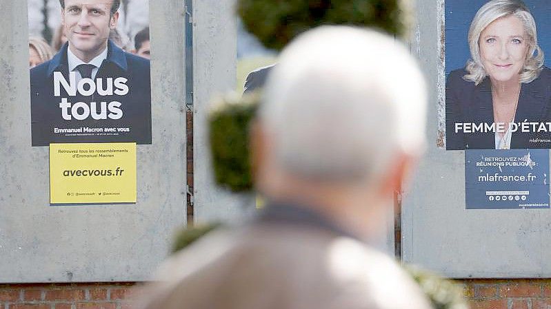 Ein Mann geht an Wahlkampfplakaten für die Präsidentschaftswahl in Frankreich vorbei. Foto: Ludovic Marin/AFP/dpa