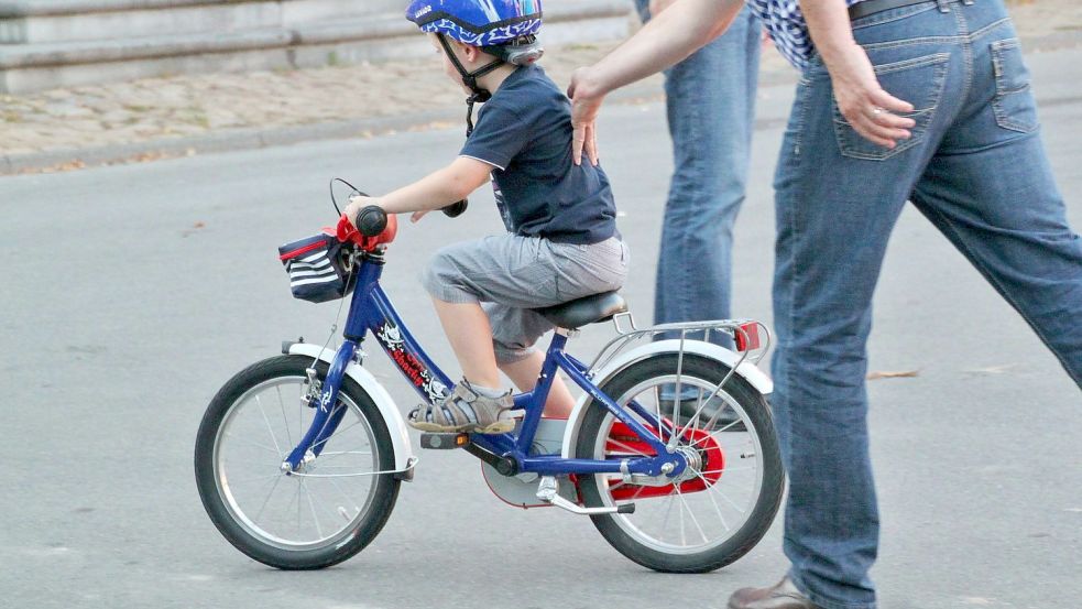 Ein Kind lernt – noch mit etwas Hilfe – das Fahrradfahren. Damit Mädchen und Jungen im Straßenverkehr so sicher wie möglich unterwegs sind, sollten ihre Räder allen Standards entsprechen – das tun viele in Emden und Leer aber nicht. Foto: Pixabay