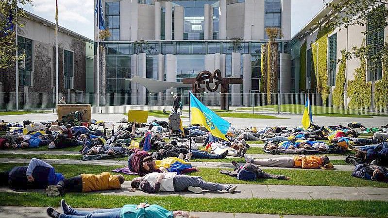 Auf dem Boden liegend protestieren diese Menschen vor dem Bundeskanzleramt gegen den Krieg in der Ukraine. Foto: Kay Nietfeld/dpa