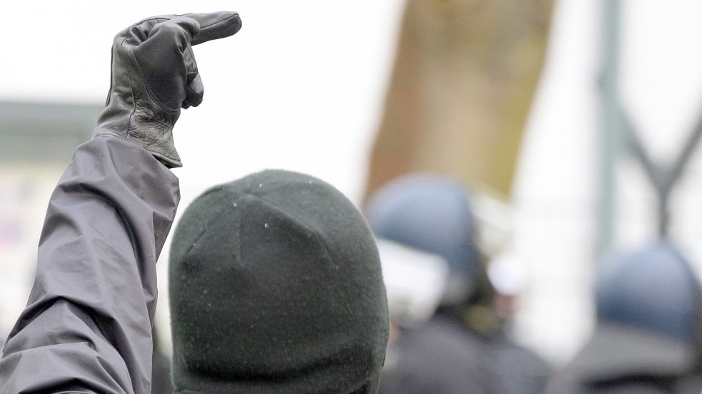 Ein schwarz gekleideter Teilnehmer der Demonstration unter dem Motto „Verboten gut - Anarchismus in die Offensive - Anarchistischer 1. Mai“ zeigt vor einer Hamburger Polizeiwache einen Stinkefinger. Foto: Walzberg/dpa