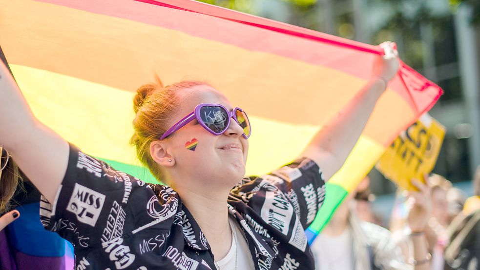 Eine Frau mit Regenbogenfahne nimmt an einer Parade zum Christopher Street Day (CSD) in Köln teil. Foto: Becker/dpa