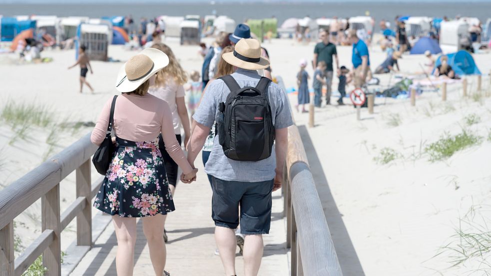 Tagesgäste auf den Weg zum Strand: Bisher konnten Touristen aus Norddeich mit der Nordsee-Servicecard auch in Bensersiel oder der Krummhörn kostenlos an den Strand. Ob das künftig noch geht, ist offen. Foto: DPA