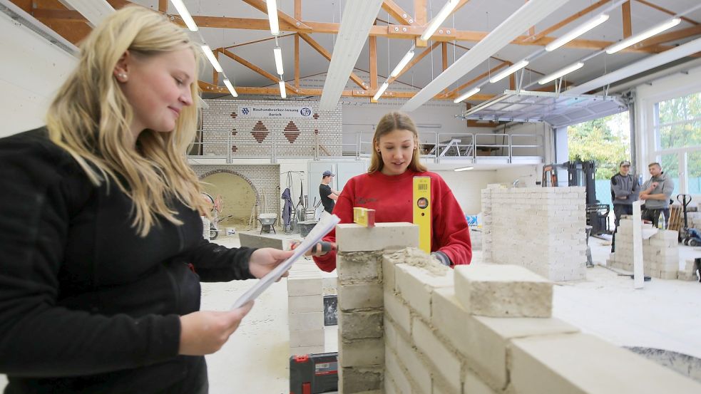 Eine Mauer und einen Pfeiler müssen Ines Reuß (16, links) und Laura Renken (19) mauern. Die beiden sind im zweiten Lehrjahr im Hochbau – lernen also Maurer. Foto: Böning