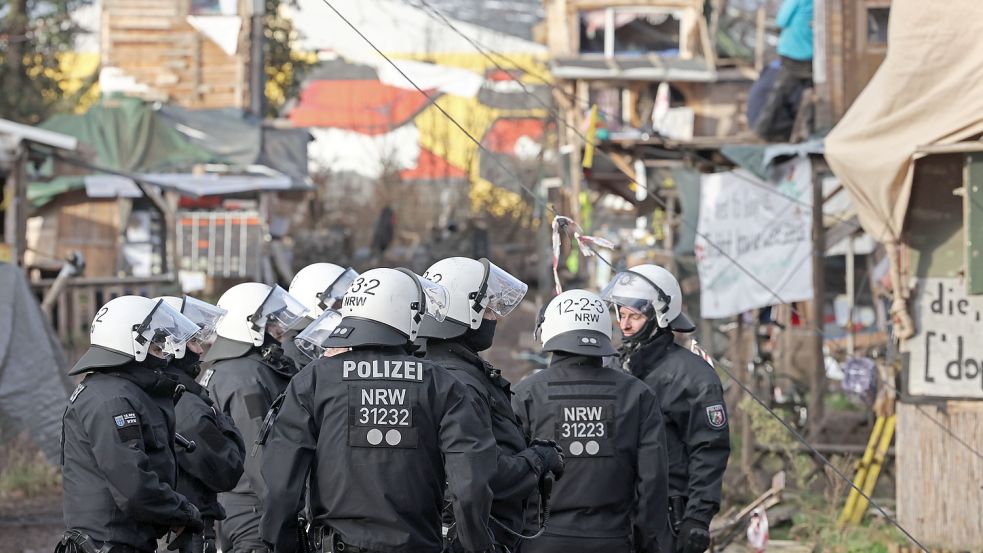 Eine Gruppe Polizisten steht bei der Räumung von Lützerath vor Bretterhütten, die von Aktivisten und Demonstranten gebaut worden waren. Foto: dpa/Rolf Vennenbernd