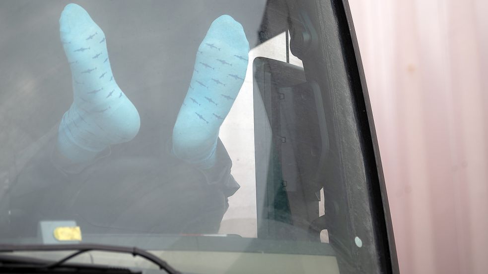 Ein Lasterfahrer rastet und drückt dabei seine Socken gegen die Frontscheibe. Wochenends dürfen Trucker ihre Ruhezeit offiziell nicht mehr in der Kabine zubringen. Foto: Gollnow/DPA