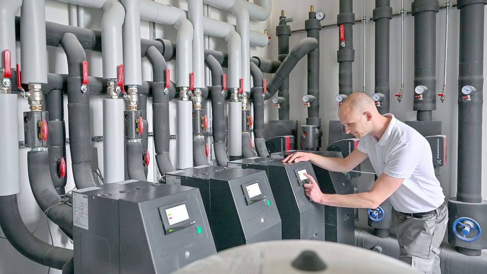 Emanuel Kaldun, Mitarbeiter der GeoClimaDesign AG, steht in einem Heizungsraum mit mehreren modernen Sole-Wasser-Wärmepumpen. In diesem Altbau, der gegenwärtig saniert wird, bekommt jeder Raum eine moderne Klimadecke mit Kapillarrohrmatten als Flächenheizung und -kühlung. Foto: Pleul/dpa