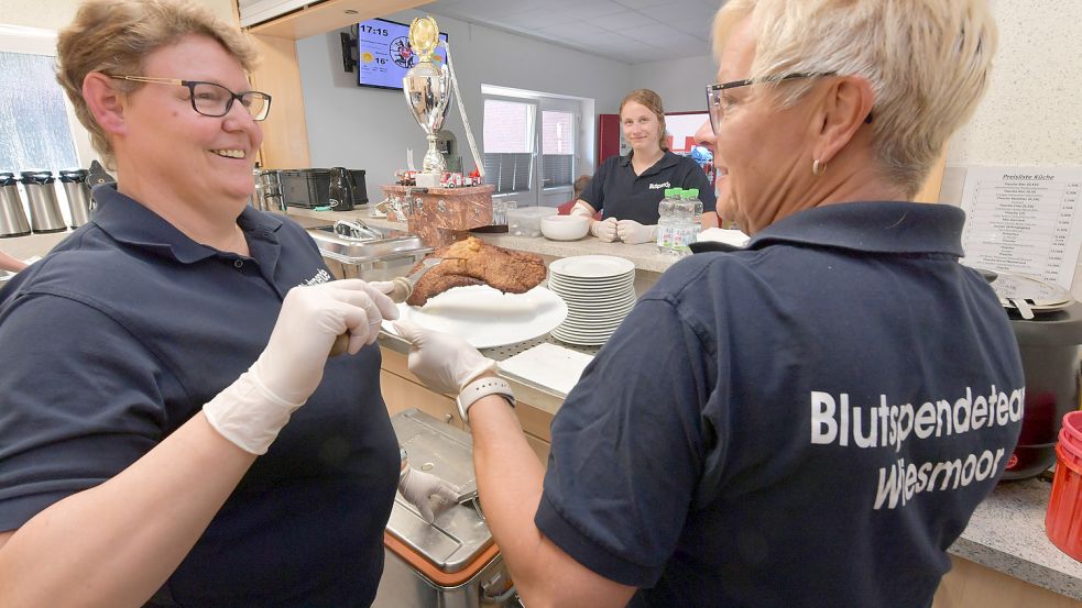 Manuela Heimbach (links) und Marianne Heinen von der Feuerwehr Wiesmoor bereiten für die Blutspender Schnitzel als Stärkung nach der Blutspende zu. Foto: Orgies