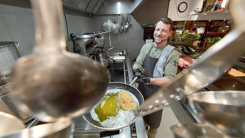 So wird Schnitzel gebraten: Der Küchenchef des Hafenhauses, Sebastian Schmidt, schwenkt das panierte Stück in viel Fett in der Pfanne. Foto: Ortgies