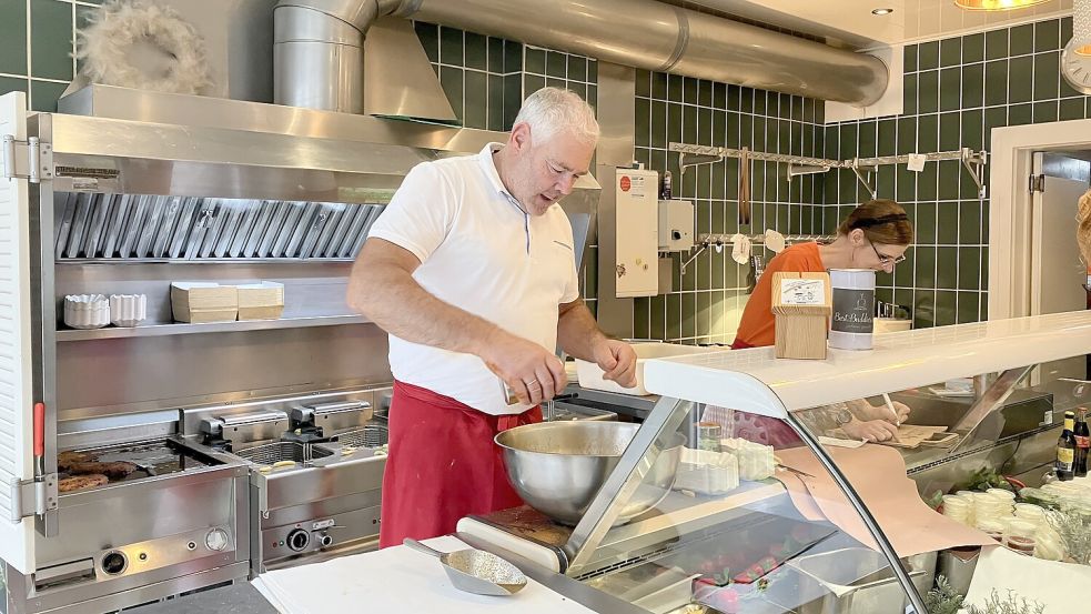 In seinem Element: Herrentorgrill-Meister Detlef Haase beim Pommeswürzen, hinter ihm brutzeln die Schnitzel. Foto: Schuurman