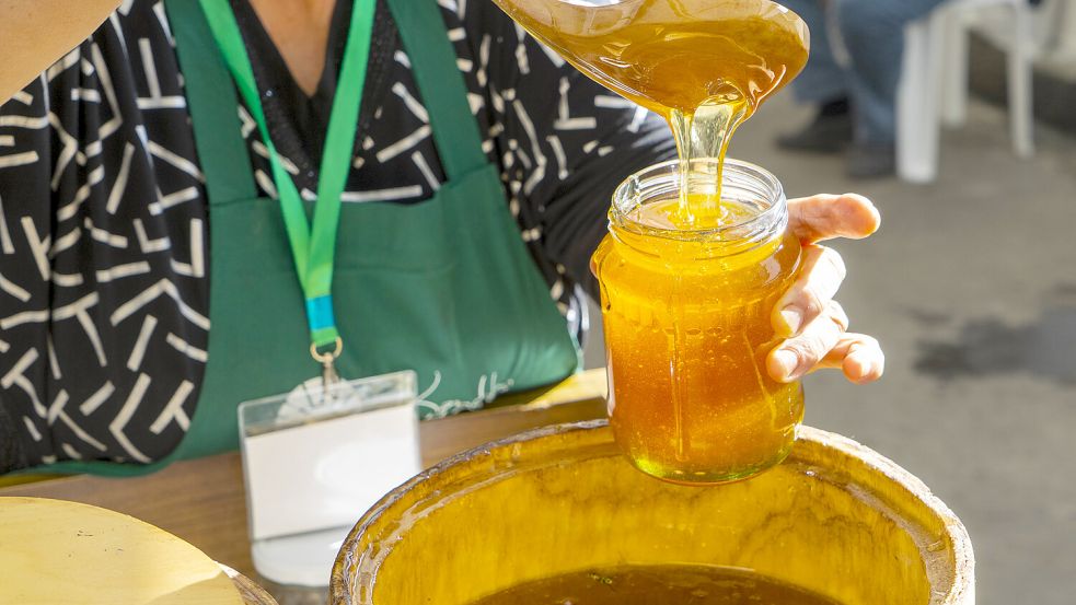 Eine Frau lässt Honig in ein Glas fließen. Künftig soll laut EU-Parlament die Transparenz für Frühstückslebensmittel erhöht werden. Foto: imago images/Cavan Images