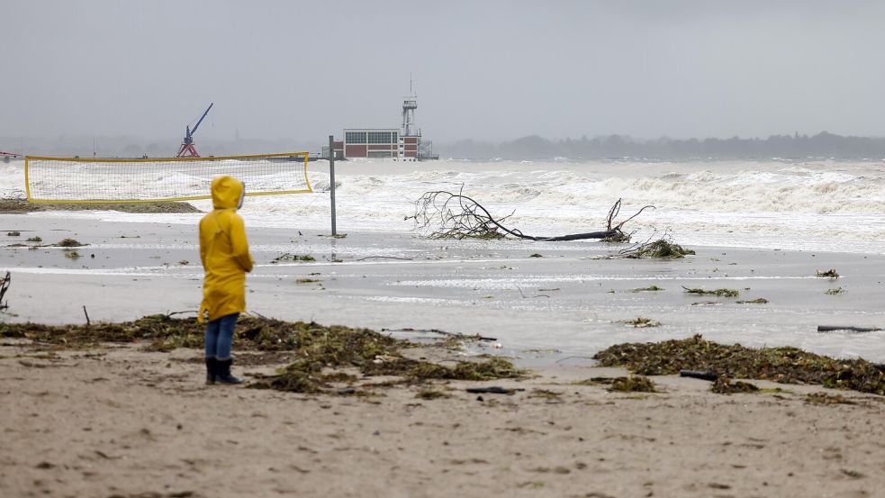 Eine Frau schaut auf die aufgewühlte See am Ostseestrand. Wegen eines Sturmtiefs sind an der Ostseeküste Straßen und Uferbereiche vom Hochwasser überschwemmt worden. Foto: Frank Molter/dpa