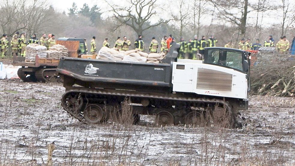 Einsatzkräfte mit schwerem Gerät sichern einen Deich nahe eines Bahndamms an der Hunte im Ortsteil Sandkrug (Gemeinde Hatten). Foto: Uwe Arndt/Nord-West-Media TV/dpa