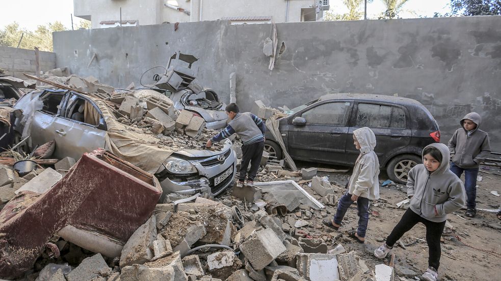 Palästinensische Kinder begutachten die Trümmer zerstörter Häuser und Fahrzeuge nach einem israelischen Bombardement. Foto: dpa/Mohammed Talatene