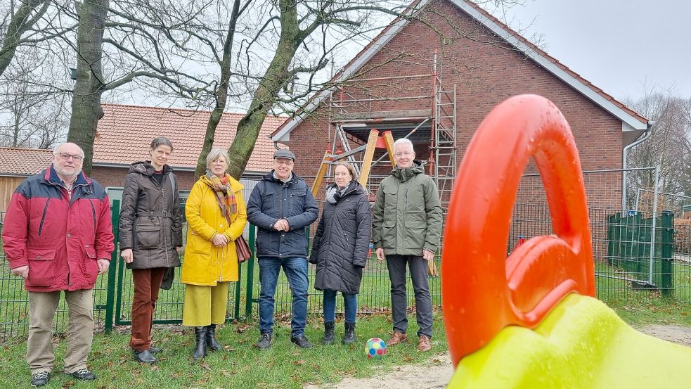 Freuen sich auf die Erweiterung der Kindertagesstätte (von links): Achim Klann (Kirchenrat), Kreisrätin Ute Buntrock, Architektin Heike de Boer, Pastor Ingo Brookmann, Kita-Leiterin Vera Boese und Landrat Matthias Groote. Das Obergeschoss des Gebäudes im Hintergrund wird ausgebaut. Foto: Bothe