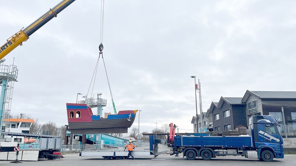 Ein Kran hat das Spielschiff am Haken. Es wird im Hafen von Bensersiel auf die Fähre nach Langeoog geladen. Foto: Awo Bezirksverband Hannover
