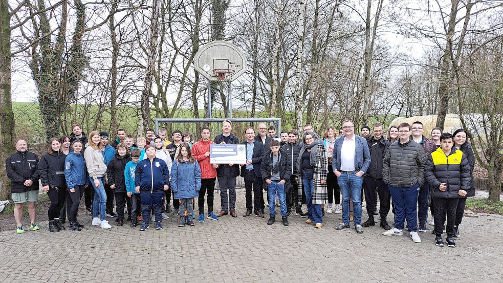 Vorsitzender Christian Brahms (Mitte), nahm den symbolischen Scheck des Lions-Clubs Leer von Präsident Dietmar Löcken und Schatzmeister Holger Franz (rechts daneben) entgegen. Mit ihm freuten sich die Schülerinnen, Schüler und Vertreter der Tagesbildungsstätte. Foto: privat