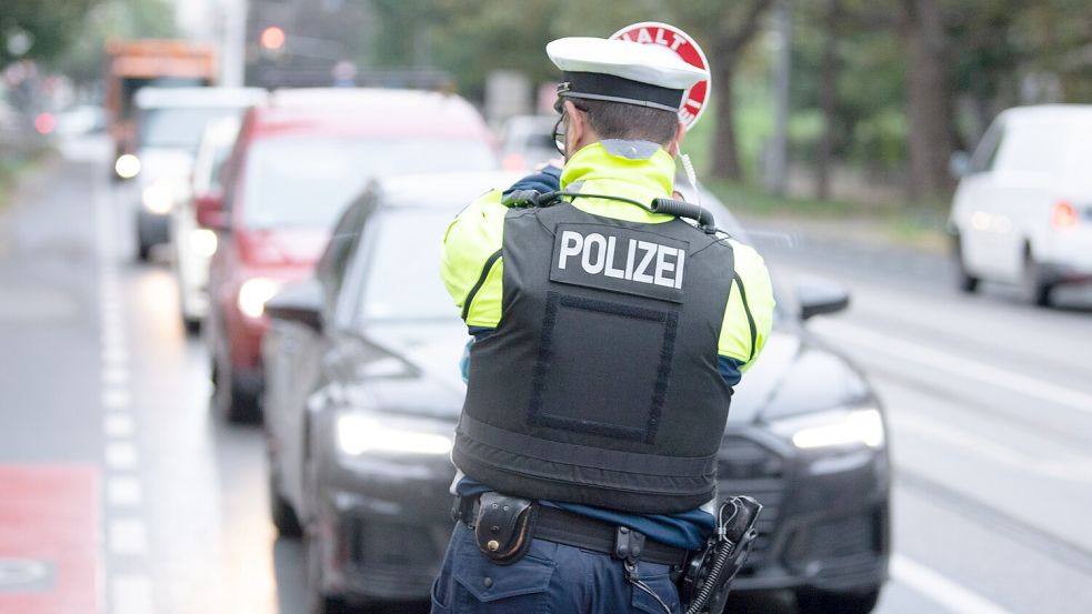 Ein Polizist steht während einer Kontrolle mit einer Winkerkelle vor mehreren Fahrzeugen. Symbolfoto: Sebastian Kahnert/dpa